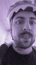 a selfie of a white person, wearing either headphones or a helmet, making an odd expression. the photo is edited to be colorized into a monochrome purple-ish color palette.