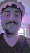 a selfie of a white person, wearing either headphones or a helmet, making an odd expression. the photo is edited to be colorized into a monochrome purple-ish color palette.