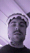 a selfie of a white person, wearing either headphones or a helmet, making an odd expression. the photo is edited to be colorized into a monochrome purple-ish color palette.